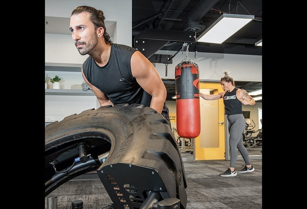 Man Flips tire and Woman Punches Punching Bag in Resident Fitness Center